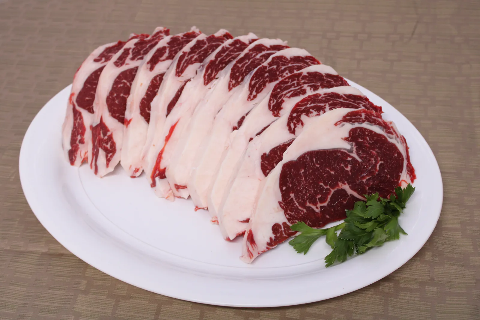 A rack of bone-in ribeyes on a platter